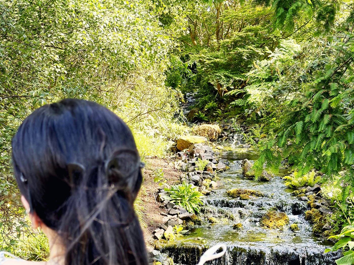Emmy Bloom beside a garden waterfall